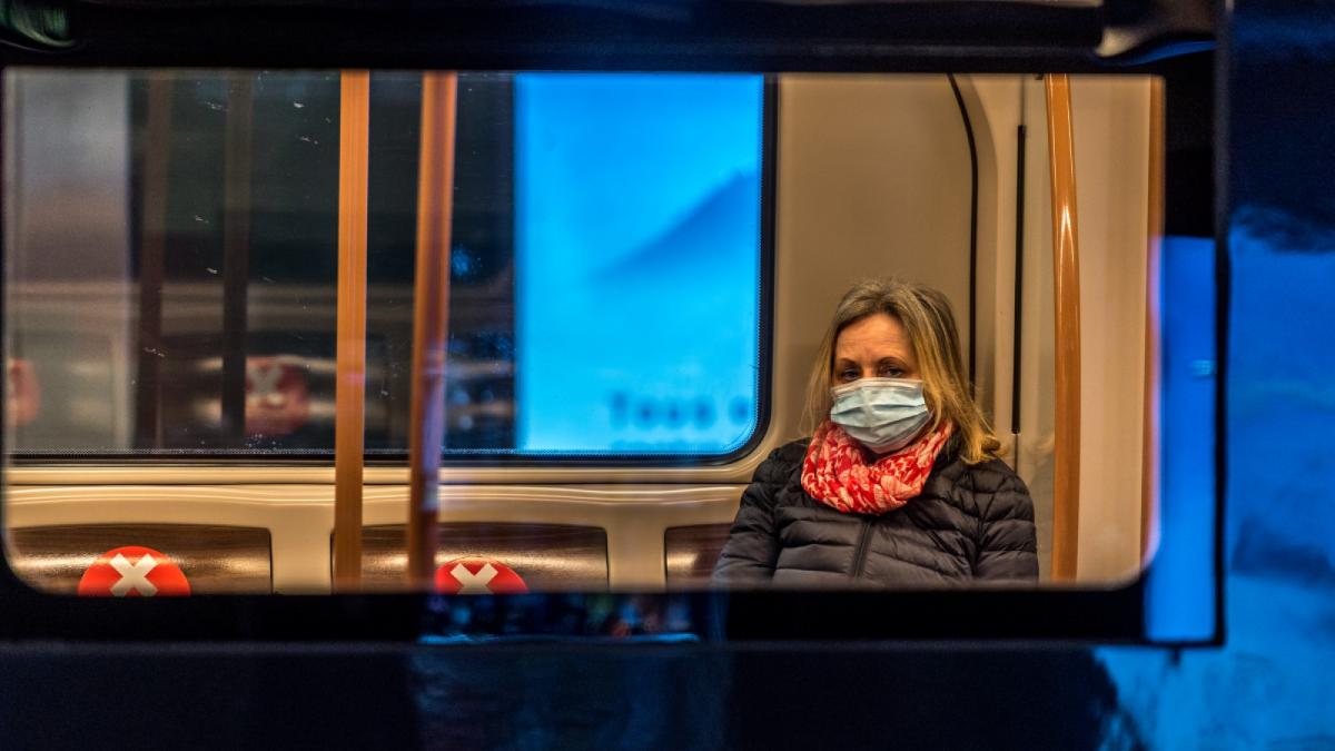 Woman with mask sitting in public transport.