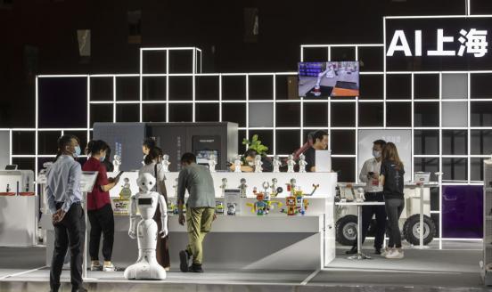 Attendees browse as a humanoid robot stands in the exhibition display area at the World AI Conference in Shanghai, China, on Thursday, July 9, 2020.