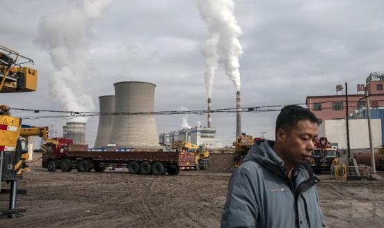 A person walks past a coal fired power plant in Jiayuguan, Gansu province, China, on Thursday, April 1, 2021.