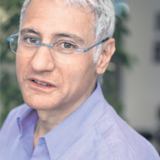 a man with grey hair, in glasses and in a purple shirt